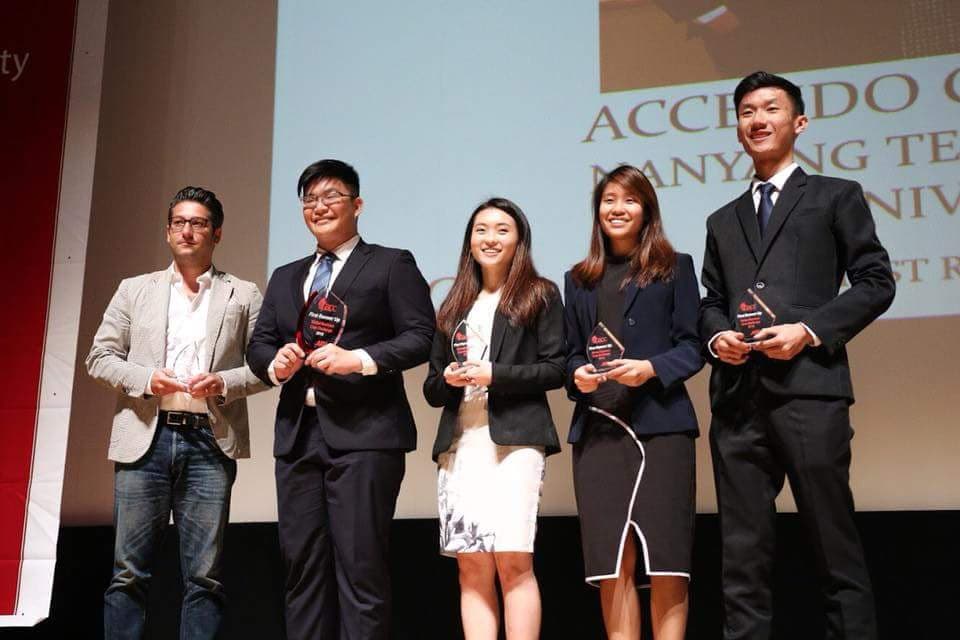 Five people on stage at a Nanyang Technological University awards ceremony, four of them holding trophies